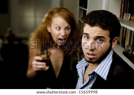 Young woman with cocktail yells at a man at party