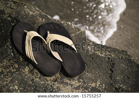 Sandals on a rock with ocean wave in the background