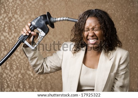 Woman holding gas nozzle like a gun to her head