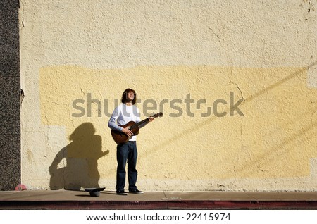 Young man on street with guitar and hat