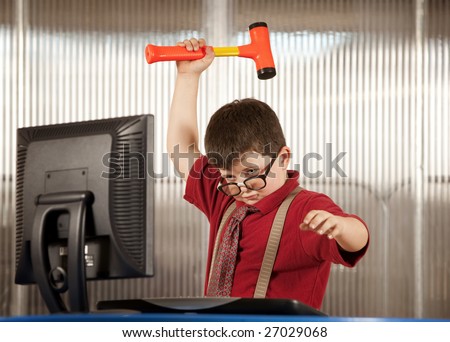 Nerdy young boy smashing his computer with a hammer