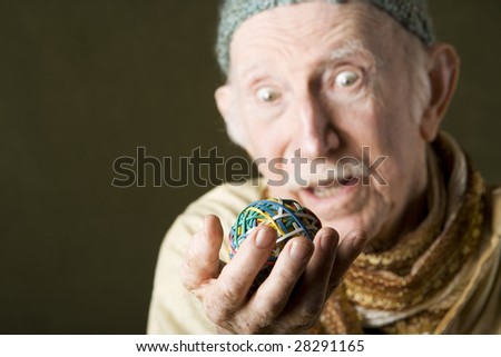 Senior man in knit cap contemplating a colorful rubber band ball