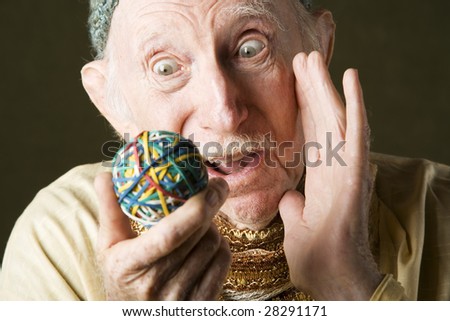 Senior man in knit cap contemplating a colorful rubber band ball
