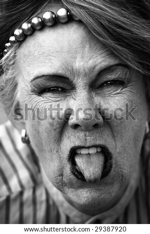 Closeup of rude old woman sticking out her tongue