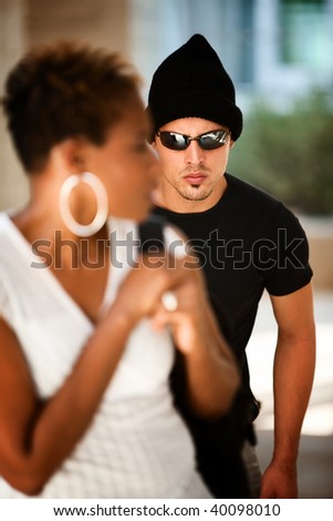 Woman being stalked by criminal in sunglasses and ski hat