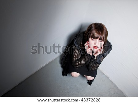Pretty Goth girl hunched down in a corner