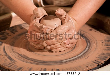 hands forming spinning clay wedge on wheel