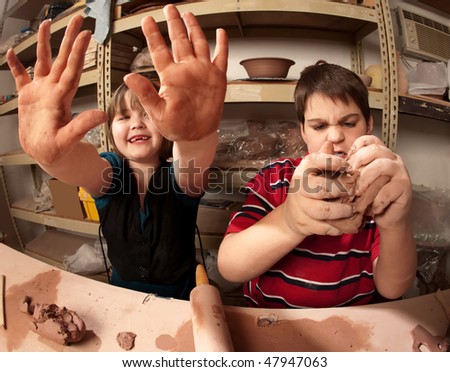 Fish-eye shot of kids with messy hands in clay studio