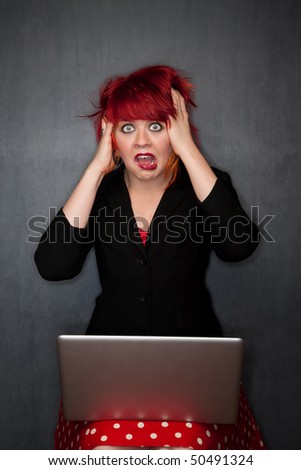 Pretty punky girl with brightly dyed red hair with laptop computer