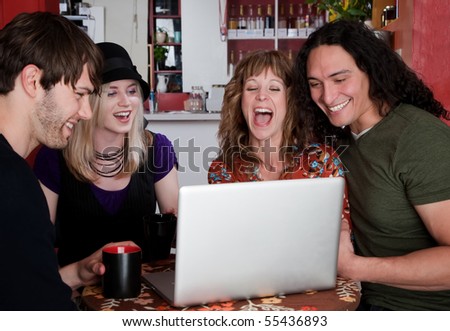 Four friends in a coffee house with laptop computer