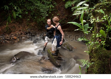 Woman helping man cross ruching Costa Rican river