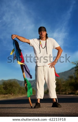 Native American man in the middle of a road with flags representing four directions