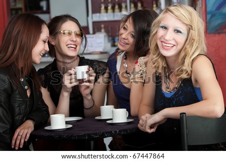 A cute blonde girl smiles while sitting with three friends in a cafe