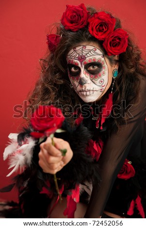 Woman dressed for All Souls Day holding out a red rose
