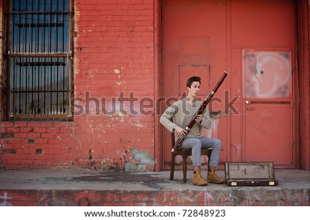 Bassoon musician with open case for money performing outdoors
