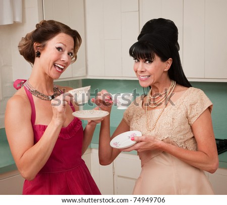 Two retro style women enjoying tea or coffee in the kitchen