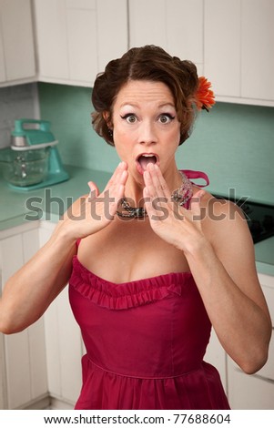 Shocked middle-aged woman in kitchen with hands by her mouth
