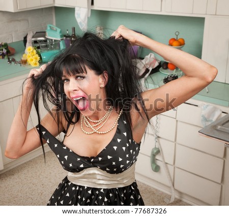 Frustrated Caucasian housewife pulls her hair in kitchen