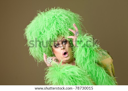 Surprised large drag queen in boa wig on green background