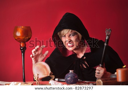 Scary witch with sceptre and crystal ball over red background