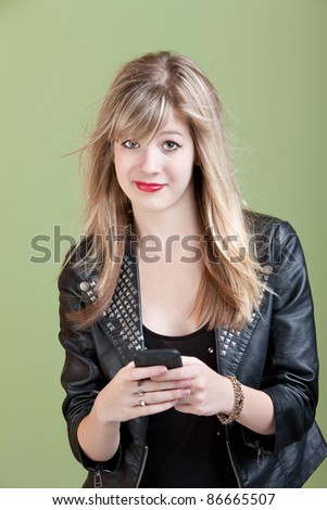 Retro-styled young woman with messy hair and cellphone over green background