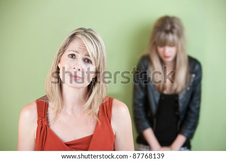 Unhappy Caucasian mom with sad daughter over green background