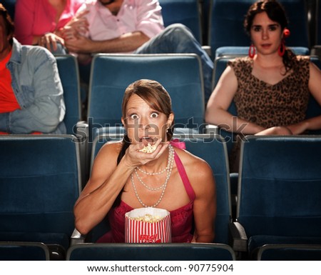 Shocked Caucasian woman eats popcorn in theater
