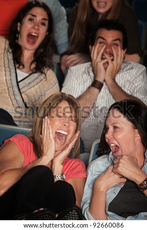 Scared group of spectators in theater seats scream in fear