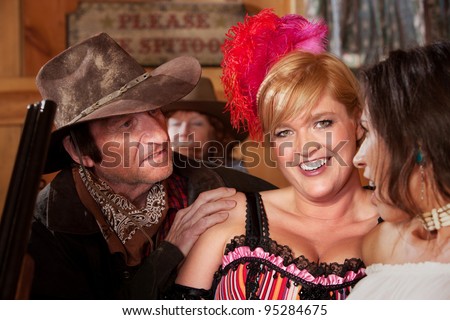 A dusty cowboy tries to talk to two lovely barmaids in the saloon.