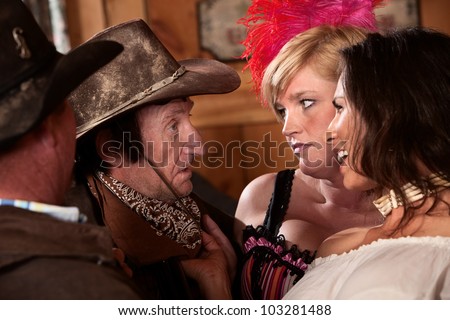 Cowboys talk with women in an old western saloon