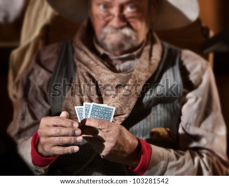Bluffing card player in old American west saloon. Hands in focus.
