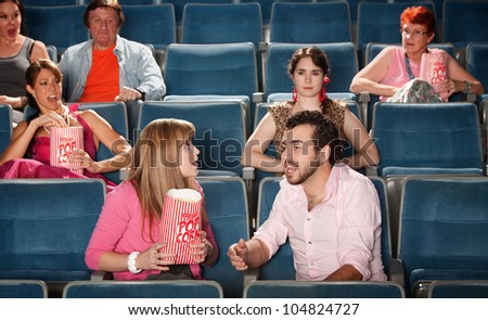 Loud couple talking with annoyed people in crowded theater