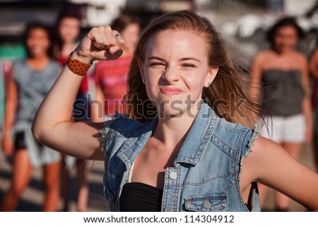 Angry young girl in denim jacket shakes her fist