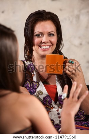Happy Caucasian brunette drinking coffee and talking with friend