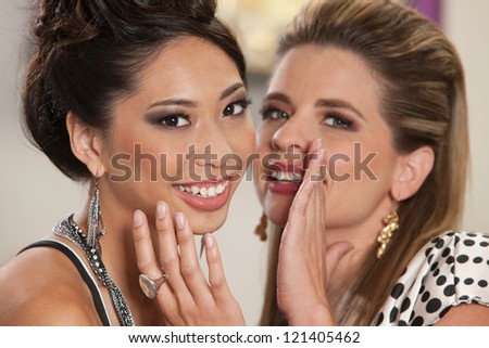 Smiling white female whispering secrets to her Asian friend