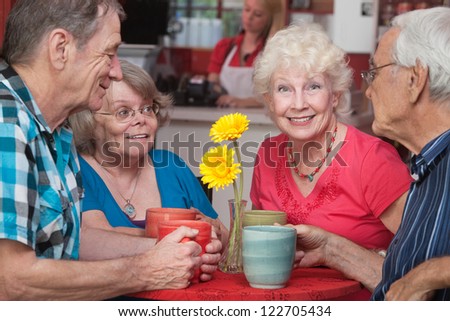 Group of four happy senior citizens at restaurant