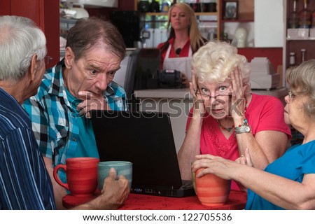 Upset elderly woman with laptop and friends helping
