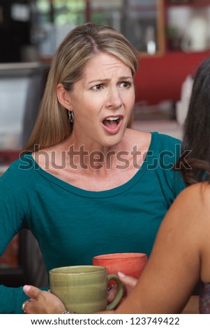 Insulted Caucasian woman across from friend in restaurant