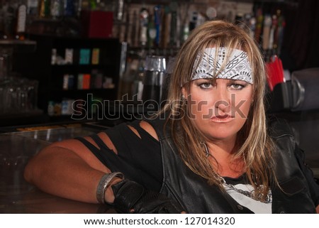 Tough woman in bandanna and leather jacket sitting in a bar