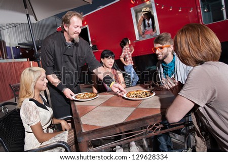 Hipster group served pizza by mobile cafe chef