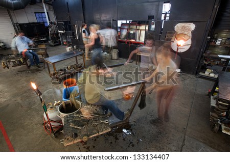 Busy workers moving in small business glass factory