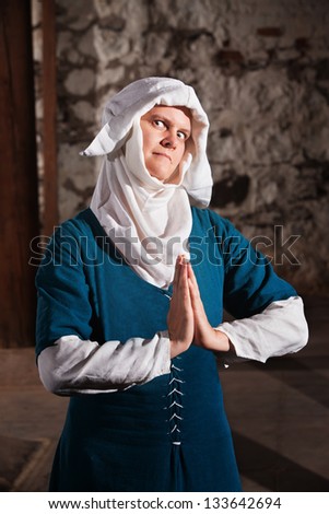 Sinister middle ages nun in blue with hands together in prayer