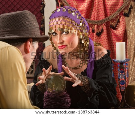 Sexy fortune teller waving hands over crystal ball