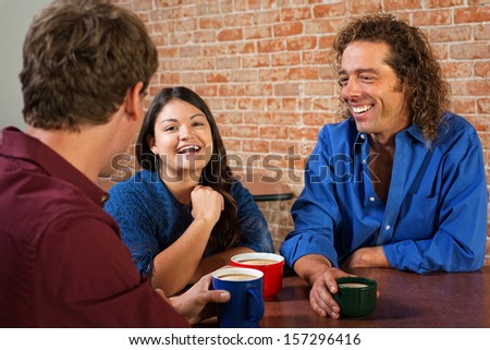 Three friends laughing and talking in coffee house