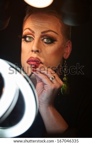 Serious Caucasian drag queen using lipstick
