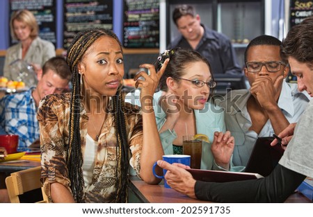 Perplexed beautiful African student studying with friends