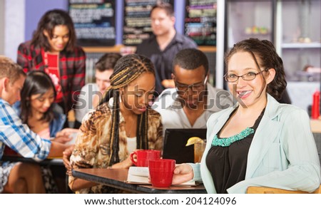 Happy young woman with students in coffee house
