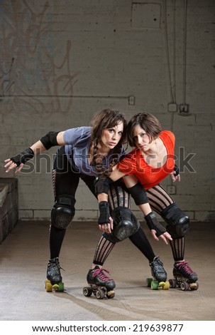 Pair of beautiful female roller derby skaters in action pose