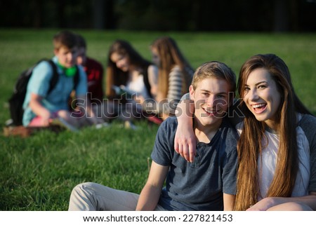Happy teen girlfriend and boyfriend sitting outdoors
