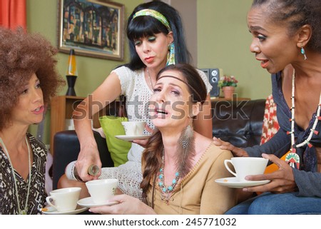 Friends pouring whiskey in teacup of crying female